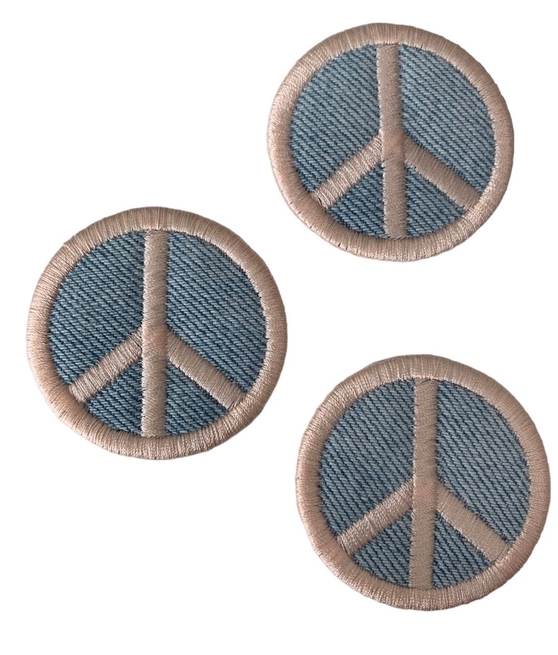 May include: Three denim peace sign patches with a light brown outline. The patches are round and have a textured denim fabric.