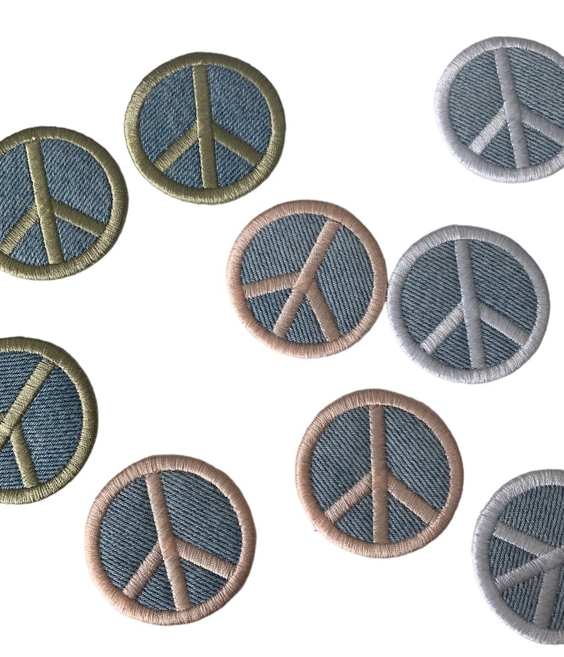 May include: Nine embroidered peace sign patches in various colors. The patches are circular and feature a white peace sign on a denim background. The patches are surrounded by a contrasting colored border.