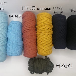 May include: A collection of colorful macrame cord spools in various shades. Colors include light blue, blue, tile, mustard, navy blue, black, and khaki. Text labels identify each color. The spools are tightly wound and ready for crafting.