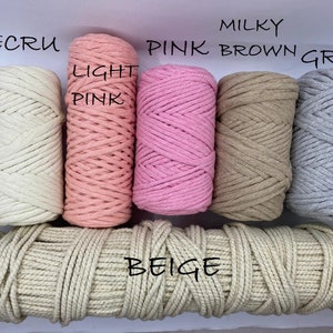 May include: A selection of macrame cord in various colors, including ecru, light pink, pink, milky brown, and grey. The word "beige" is written across a length of beige cord. The image showcases the different color options available.
