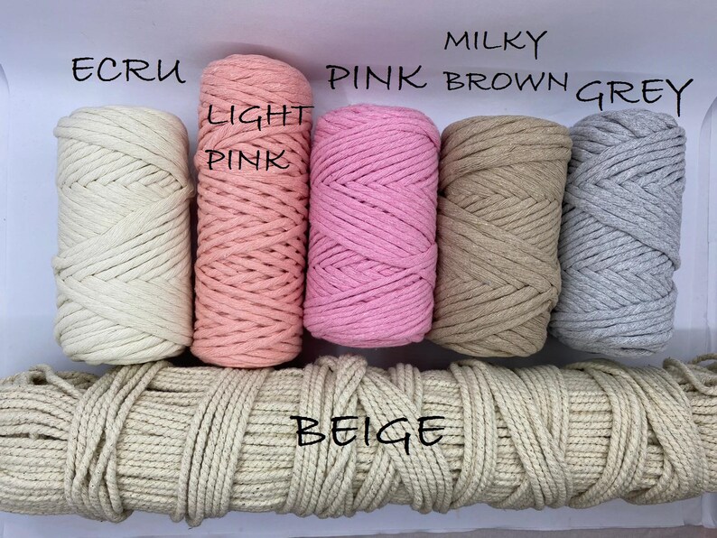 May include: A selection of macrame cord in various colors, including ecru, light pink, pink, milky brown, and grey. The word "beige" is written across a length of beige cord. The image showcases the different color options available.