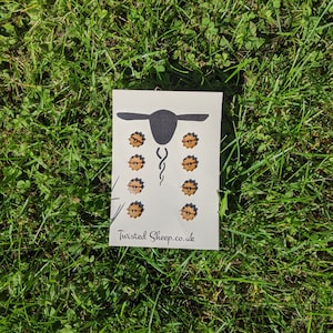 May include: A white card with a black silhouette of a sheep with eight wooden buttons in the shape of a flower. The text "Twisted Sheep.co.uk" is printed at the bottom of the card.