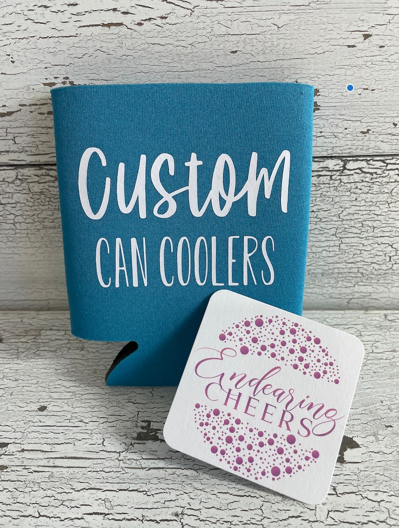 May include: A turquoise blue can cooler with the text "Custom Can Coolers" in white lettering. A white square coaster with pink polka dots and the text "Endearing Cheers" in pink cursive lettering.