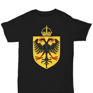 Puede incluir: Camiseta negra con una corona dorada y un águila bicéfala negra sobre un escudo amarillo.