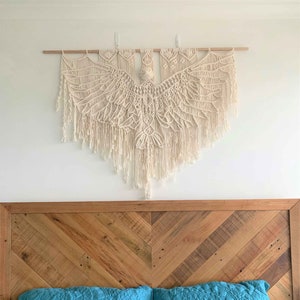 Large macrame bird wall hanging sits above a queen bed with a wooden headboard. The Eagle is over 1 metre wide and 1 metre long at its longest point.