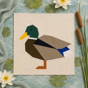 May include: A square fabric quilt block featuring a geometric mallard duck appliqué. The duck has a dark green head, a bright yellow beak, a brown chest, tan wings, a black stripe, and blue and white tail feathers, standing on orange feet.