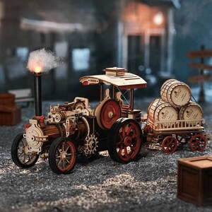 Può includere: Un modello in legno di una macchina a vapore vintage, dipinta in rosso e nero. La macchina tira un carro carico di tre barili di legno etichettati con "1882".