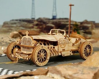 Könnte beinhalten: Ein Holzmodellbausatz eines Oldtimer-Rennwagens mit detailliertem Motor und Rädern. Das Auto ist in natürlicher Holzfarbe lackiert und trägt die Nummer "32" an der Seite.