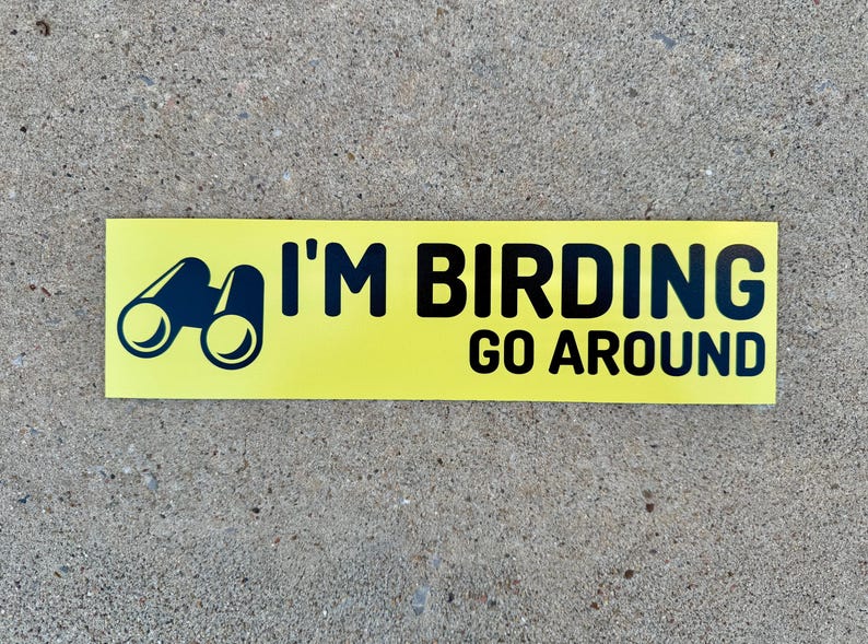 Op de afbeelding: Gele sticker met zwarte tekst en een zwart silhouet van een verrekijker. De tekst luidt "I'm Birding Go Around".