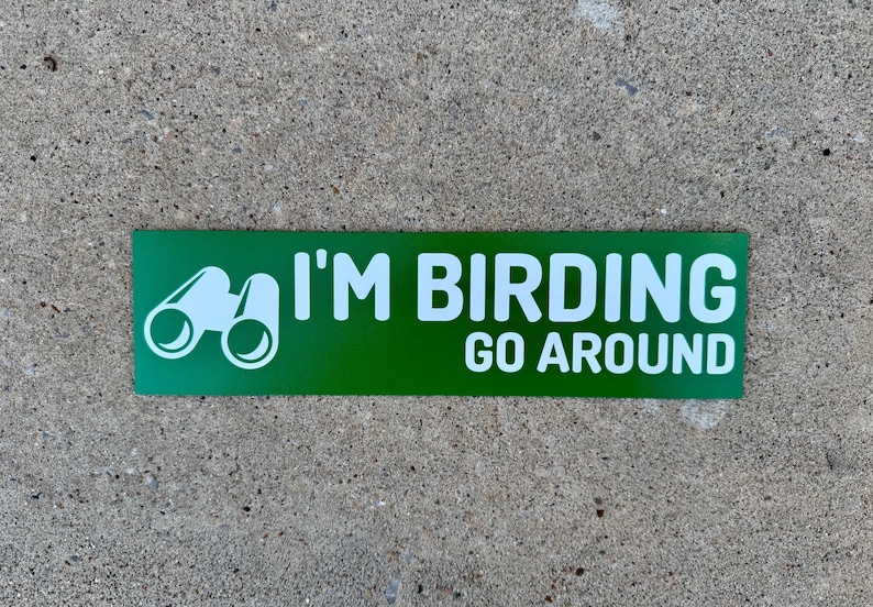 Op de afbeelding: Groene rechthoekige sticker met witte tekst die "I'm Birding Go Around" zegt en een wit silhouet van een verrekijker.
