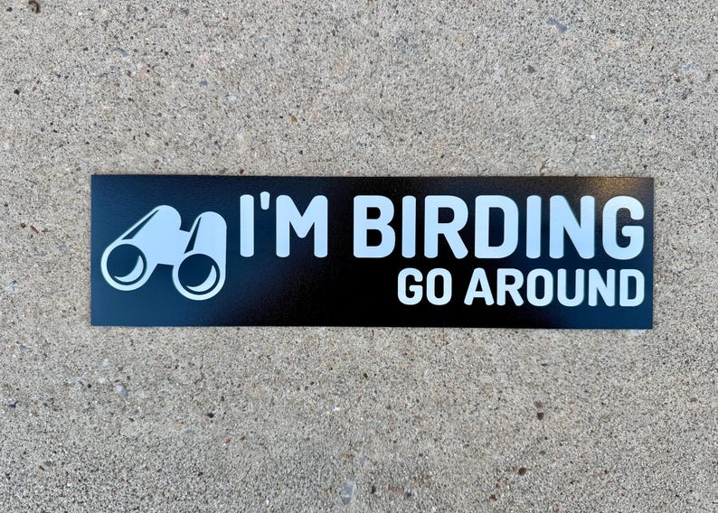 Op de afbeelding: Zwarte en witte sticker met een verrekijker en de tekst "I'M BIRDING GO AROUND".