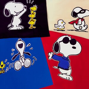 K&ouml;nnte beinhalten: Eine Collage aus vier bunten Quadraten mit verschiedenen Cartoon-Bildern von Snoopy, der Peanuts-Figur. Das obere linke Quadrat zeigt Snoopy in Schwarzwei&szlig;, auf seinen Hinterbeinen stehend, mit erhobenen Armen. Das obere rechte Quadrat zeigt Snoopy in Schwarzwei&szlig;, einen blauen Pullover tragend und auf seinen Hinterbeinen stehend. Das untere linke Quadrat zeigt Snoopy in Schwarzwei&szlig;, einen blauen Pullover tragend und auf seinen Hinterbeinen stehend. Das untere rechte Quadrat zeigt Snoopy in Schwarzwei&szlig;, einen blauen Pullover tragend und auf seinen Hinterbeinen stehend.