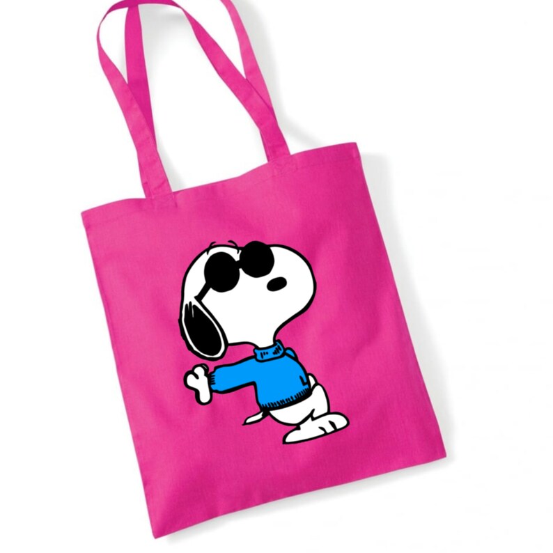 K&ouml;nnte beinhalten: Rosa Einkaufstasche mit einem Cartoon-Bild von Snoopy, der eine Sonnenbrille und einen blauen Pullover tr&auml;gt.