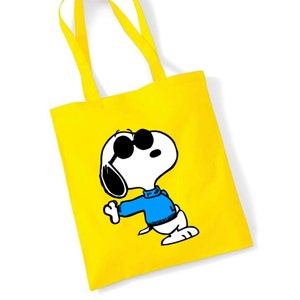 K&ouml;nnte beinhalten: Gelbe Einkaufstasche mit einem Cartoon-Bild von Snoopy, der eine Sonnenbrille und einen blauen Pullover tr&auml;gt.