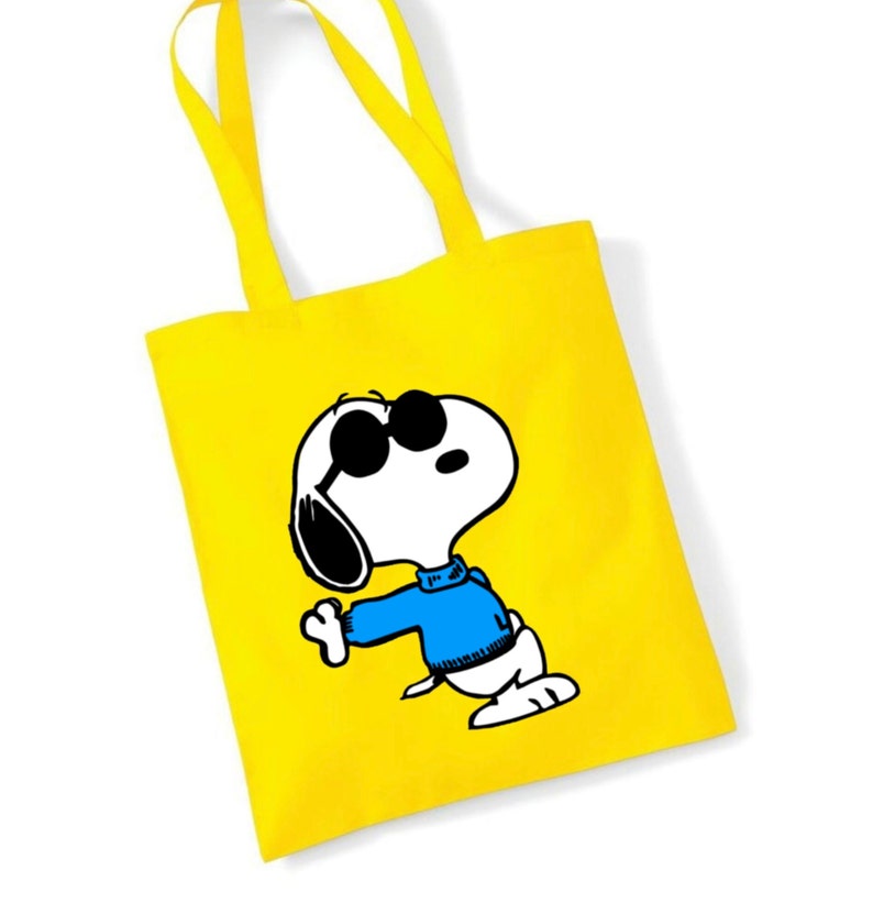 K&ouml;nnte beinhalten: Gelbe Einkaufstasche mit einem Cartoon-Bild von Snoopy, der eine Sonnenbrille und einen blauen Pullover tr&auml;gt.