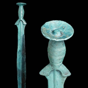 May include: A bronze sword with a decorative handle and a circular pommel. The sword is a teal green color and has intricate designs on the handle.
