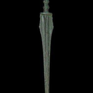 May include: A bronze dagger with a long, slender blade and a detailed handle. The handle features a series of ridges and a flared base. The dagger has a dark green patina, suggesting age. The background is solid black.