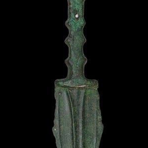 May include: A detailed image of an antique bronze dagger with a green patina. The dagger features a flared handle, a ridged grip, and a leaf-shaped blade. The background is solid black.