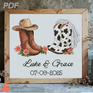 May include: A cross-stitch pattern featuring a brown cowboy hat resting on brown leather boots next to white and black cow-print boots with a veil. Pink flowers accent the base. The text reads Luke & Grace and the date 07-09-2025.
