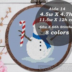 May include: Cross stitch pattern of a snowman holding a candy cane. The pattern is on Aida 14 fabric and measures 4.5 inches wide by 4.7 inches high. The pattern uses 8 colors and is 64 stitches wide by 66 stitches high.