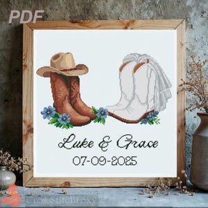 May include: Cross-stitch design featuring a pair of brown cowboy boots with a hat and white bridal boots with a veil. Blue flowers and greenery are at the base of the boots. The names "Luke & Grace" and the date "07-09-2025" are below the boots. The design is in a wooden frame.