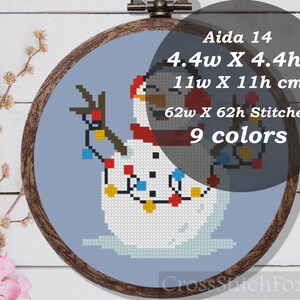 May include: Cross stitch pattern of a snowman wearing a red scarf and hat with a string of colorful lights. The pattern is for Aida 14 fabric and measures 4.4 inches wide by 4.4 inches high, or 11 cm wide by 11 cm high. The pattern requires 62 stitches wide by 62 stitches high and uses 9 colors.
