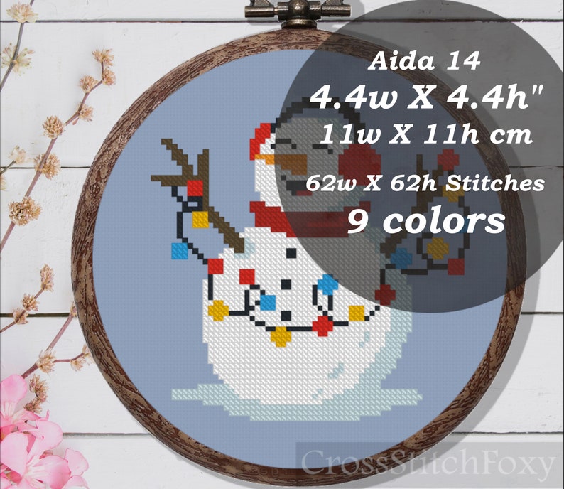 May include: Cross stitch pattern of a snowman wearing a red scarf and hat with a string of colorful lights. The pattern is for Aida 14 fabric and measures 4.4 inches wide by 4.4 inches high, or 11 cm wide by 11 cm high. The pattern requires 62 stitches wide by 62 stitches high and uses 9 colors.