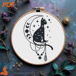 May include: A black cat silhouette cross-stitch design sits on a crescent moon, surrounded by stars. The design is framed in a wooden embroidery hoop. The text "CrossStitchFoxy" is at the bottom.