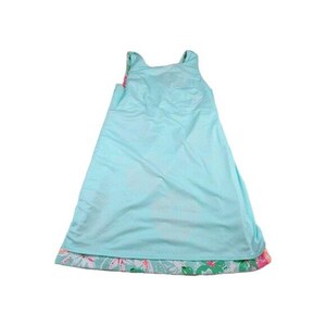May include: A sleeveless, light blue dress with a floral patterned hemline. The dress has a simple, A-line silhouette and is made of a lightweight fabric. The hemline features a colorful floral print with pink and green accents.