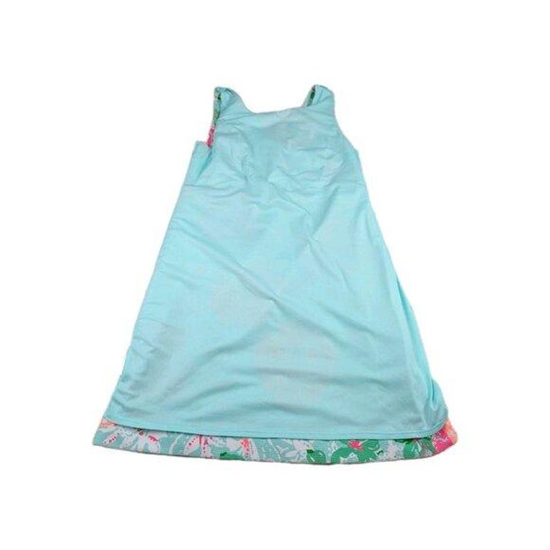 May include: A sleeveless, light blue dress with a floral patterned hemline. The dress has a simple, A-line silhouette and is made of a lightweight fabric. The hemline features a colorful floral print with pink and green accents.