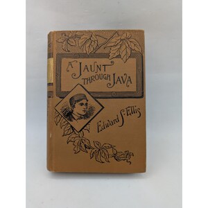 Può includere: Un libro con copertina rigida color marrone chiaro intitolato A Jaunt Through Java di Edward S. Ellis. La copertina presenta illustrazioni a inchiostro nero di foglie di vite e un ritratto a forma di diamante di una persona con un berretto.