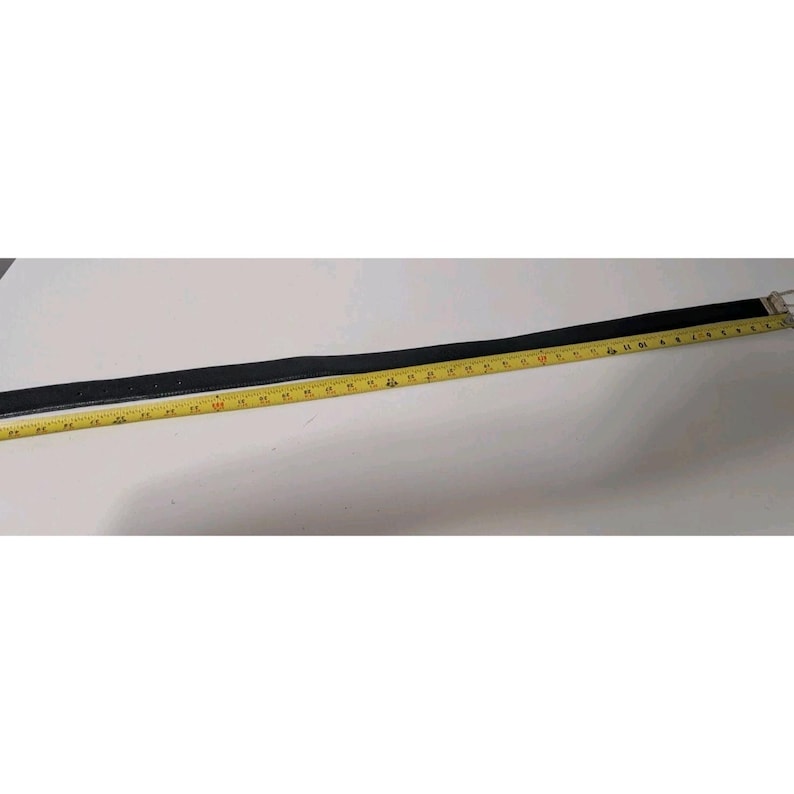 May include: A black belt with a silver buckle is laid out next to a yellow measuring tape. The belt appears to be made of leather and is approximately 40 inches long.