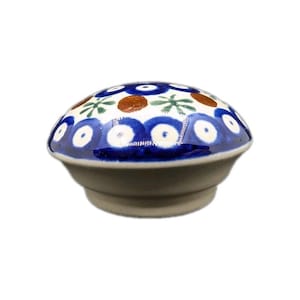 May include: A ceramic knob with a rounded top and a base. The top is white with a blue and brown floral pattern. The knob is likely for a cabinet or drawer and is a decorative accent.