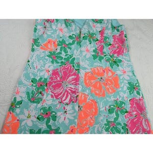 May include: A strapless dress featuring a vibrant floral pattern. The dress showcases large pink and orange flowers with green leaves against a light blue background. The dress has a zipper down the back.