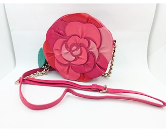 May include: A pink leather crossbody bag shaped like a rose with a gold chain strap.