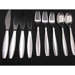 Könnte beinhalten: Ein Set aus Edelstahlbesteck, darunter Messer, Gabeln und Löffel. Das Besteck hat ein schlichtes, modernes Design mit abgerundeten Griffen und einer polierten Oberfläche. Die Messer, Gabeln und Löffel sind auf einer schwarzen Oberfläche angeordnet.