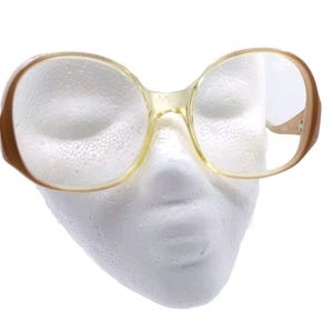 May include: A pair of large, round, clear, plastic framed glasses with brown temples.