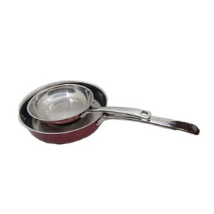 Op de afbeelding: Drie roestvrijstalen koekenpannen van verschillende formaten die in elkaar zijn genest. De grootste pan is bordeauxrood, de middelste pan is rood en de kleinste pan is zilver. De pannen hebben zilveren handvatten.