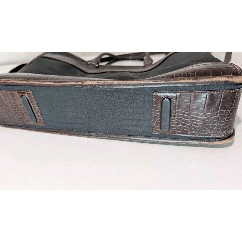 May include: A brown leather tote bag with a black canvas body and a crocodile embossed design on the bottom.