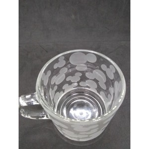 Peut inclure: Une tasse en verre transparent avec une anse. La tasse a un motif givr&eacute; de t&ecirc;tes de Mickey Mouse.