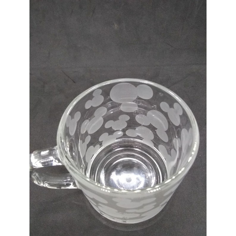 Peut inclure: Une tasse en verre transparent avec une anse. La tasse a un motif givr&eacute; de t&ecirc;tes de Mickey Mouse.