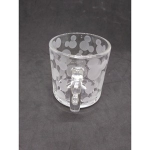 Peut inclure: Une tasse en verre transparent avec une anse. La tasse est d&eacute;cor&eacute;e d'un motif givr&eacute; de t&ecirc;tes de Mickey Mouse.