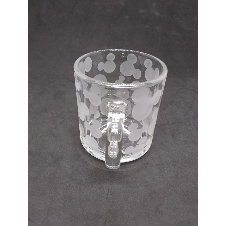 Peut inclure: Une tasse en verre transparent avec une anse. La tasse est d&eacute;cor&eacute;e d'un motif givr&eacute; de t&ecirc;tes de Mickey Mouse.
