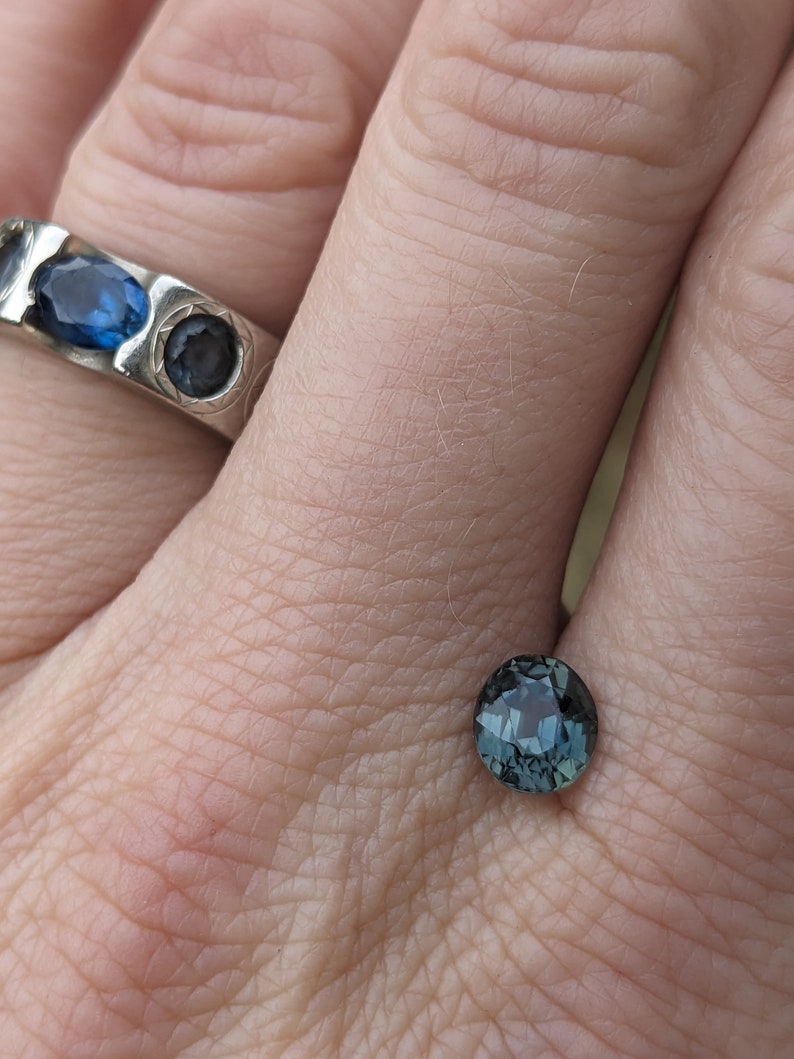 May include: A dark blue gemstone ring with a round cut. The ring is set in silver and has a textured band.