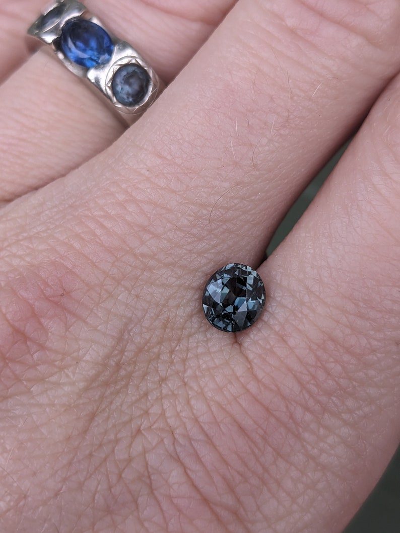 May include: A dark blue gemstone with a faceted cut, set in a ring.