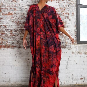 May include: A long, red and black tie-dye kaftan with side slits. The kaftan is made of a soft, flowing fabric.