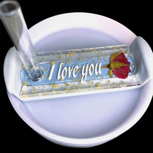 May include: A white tumbler with a blue and gold resin insert that says "I love you" with a dried red rose. The insert is designed to hold a straw.