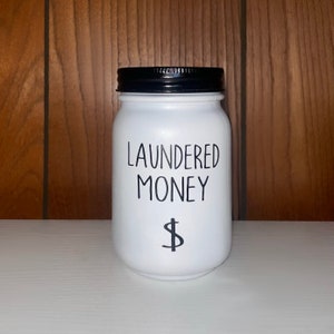 May include: White ceramic jar with a black lid and the text "LAUNDERED MONEY" and a dollar sign.