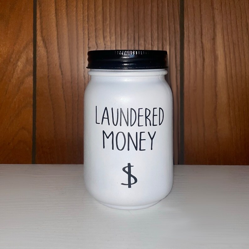 May include: White ceramic jar with a black lid and the text "LAUNDERED MONEY" and a dollar sign.