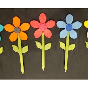 May include: Five colorful felt flower decorations. Each flower has a different color petal: turquoise, orange, red, light blue, and yellow. The centers are blue, gray, pink, blue, and green. Green stems and leaves complete the design.